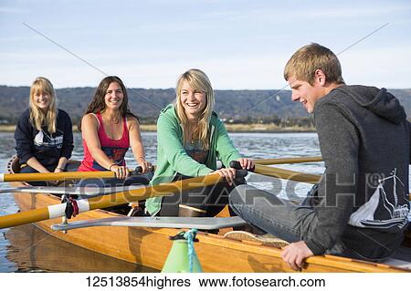 Stock Photograph - Young adults rowing in a canoe, South-central Alaska; Homer, Alaska, United States of America. Fotosearch