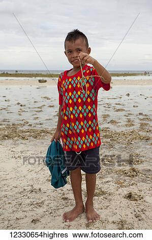 Stock Photograph - Young Boy Holds A Brittle Sea Star Out Of The Water; Anda, Bohol, Central Visayas, Philippines. Fotosearch
