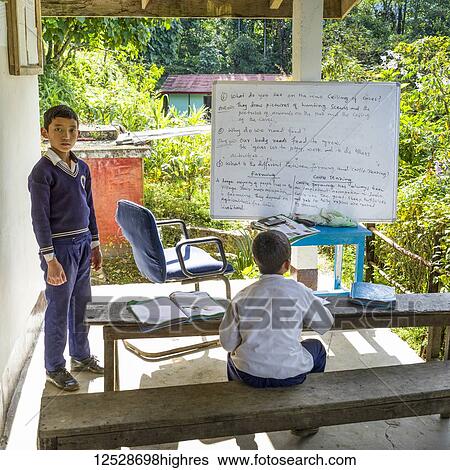 Stock Photograph - Young boys study lessons from a whiteboard at school; Dentam Forest Block, Sikkim, India. Fotosearch