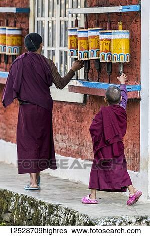 Young Buddhist monks walk by and touch the prayer wheels at Rinchenpong Monastery; Sikkim, India View Large Photo Image Stock Photograph - Young Buddhist monks walk by and touch the prayer wheels at Rinchenpong Monastery; Sikkim, India. Fotosearch