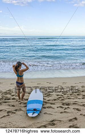 Young female surfer prepares on the beach to go out to the water; Honolulu, Oahu, Hawaii, United States of America View Large Photo Image Stock Photograph - Young female surfer prepares on the beach to go out to the water; Honolulu, Oahu, Hawaii, United States of America. Fotosearch