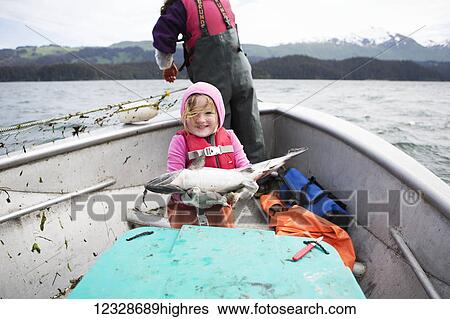 Young girl holding a fresh caught salmon while in her family's set-net skiff with her mother, Seldovia, South-central Alaska; Alaska, United States of America View Large Photo Image Stock Photograph - Young girl holding a fresh caught salmon while in her family's set-net skiff with her mother, Seldovia, South-central Alaska; Alaska, United States of America. Fotosearch