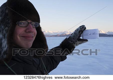 Young man showing off drawing of Kenai Mountains and holding notepad with the range in the background while standing in the snow at sunset, South-central Alaska; Alaska, United States of America View Large Photo Image Stock Photograph - Young man showing off drawing of Kenai Mountains and holding notepad with the range in the background while standing in the snow at sunset, South-central Alaska; Alaska, United States of America. Fotosearch