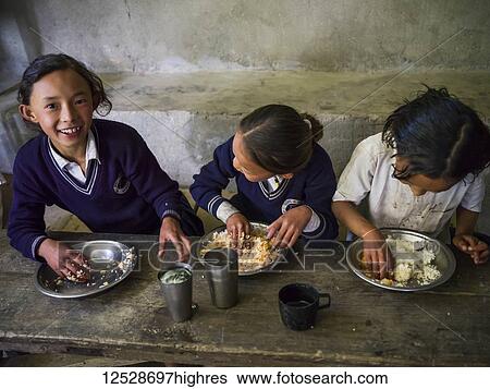 Stock Photograph - Young students in uniforms eating a meal; Dentam Forest Block, Sikkim, India. Fotosearch