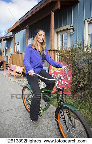 Stock Photograph - Young woman on a bicycle in downtown Anchorage, South-central Alaska; Anchorage, Alaska, United States of America. Fotosearch