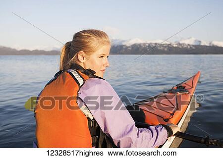 Stock Photograph - Young woman sea kayaking in Kachemak Bay, near Homer, South-central Alaska; Alaska, United States of America. Fotosearch