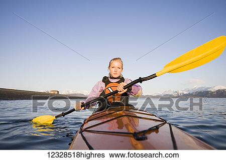 Stock Photograph - Young woman sea kayaking in Kachemak Bay, near Homer, South-central Alaska; Alaska, United States of America. Fotosearch