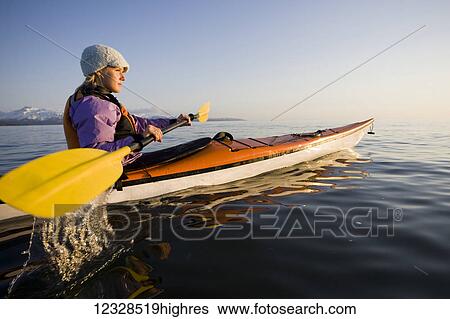 Stock Photograph - Young woman sea kayaking in Kachemak Bay, near Homer, South-central Alaska; Alaska, United States of America. Fotosearch