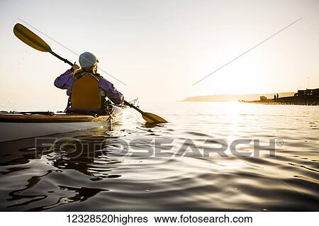 Stock Photograph - Young woman sea kayaking in Kachemak Bay, near Homer, South-central Alaska; Alaska, United States of America. Fotosearch