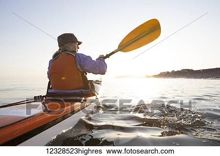 Stock Photograph - Young woman sea kayaking in Kachemak Bay, near Homer, South-central Alaska; Alaska, United States of America. Fotosearch