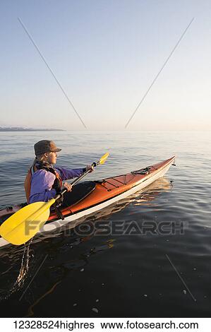 Stock Photograph - Young woman sea kayaking in Kachemak Bay, near Homer, South-central Alaska; Alaska, United States of America. Fotosearch