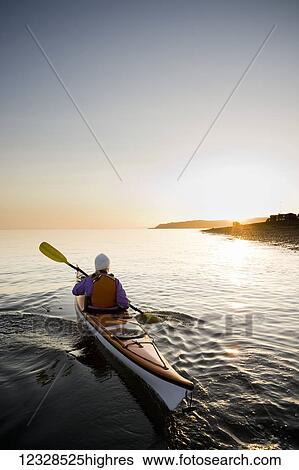 Stock Photograph - Young woman sea kayaking in Kachemak Bay, near Homer, South-central Alaska; Alaska, United States of America. Fotosearch