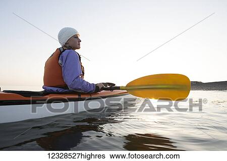 Stock Photograph - Young woman sea kayaking in Kachemak Bay, near Homer, South-central Alaska; Alaska, United States of America. Fotosearch
