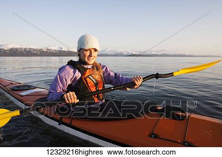 Stock Photograph - Young woman sea kayaking in Kachemak Bay, South-central Alaska, USA. Fotosearch