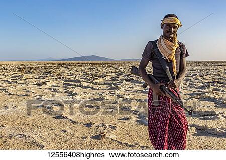Afar man carrying a gun in the salt flats of Lake Karum (Lake Assale), Danakil Depression; Afar Region, Ethiopia View Large Photo Image Stock Photograph - Afar man carrying a gun in the salt flats of Lake Karum (Lake Assale), Danakil Depression; Afar Region, Ethiopia. Fotosearch