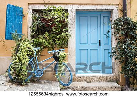 Stock Photograph - Blue bicycle displaying plants parked outside a house with a blue door on Grisia Street, famous for its cascading stone stairs; Rovinj, Croatia. Fotosearch