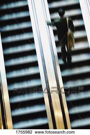 Businessperson going up an escalator View Large Photo Image Stock Image - Businessperson going up an escalator. Fotosearch