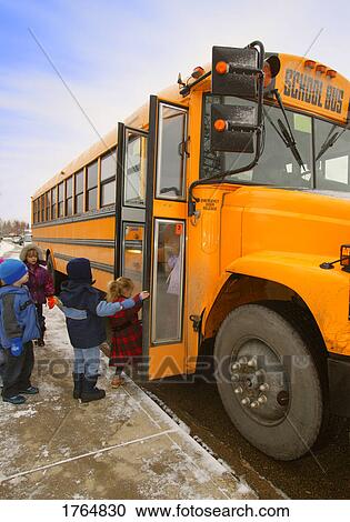 Stock Image - Elementary schoolchildren boarding school bus on a winter day in Edmonton Alberta Canada. Fotosearch