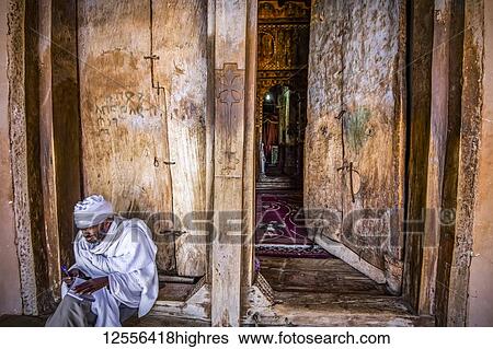 Stock Photograph - Ethiopian Orthodox priest at the entrance of Abreha we Atsbeha rock-hewn church, Tigray, Ethiopia. Fotosearch