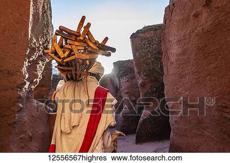 Ethiopian Orthodox priest carrying prayer sticks by Biete Qeddus Mercoreus (House of Saint Mercurius or House of Mark the Evangelist) Ethiopian Orthodox rock-cut church in the Southern Group of the Rock-Hewn Churches; Lalibela, Amhara Region, Ethiopia View Large Photo Image Stock Photograph - Ethiopian Orthodox priest carrying prayer sticks by Biete Qeddus Mercoreus (House of Saint Mercurius or House of Mark the Evangelist) Ethiopian Orthodox rock-cut church in the Southern Group of the Rock-Hewn Churches; Lalibela, Amhara Region, Ethiopia. Fotosearch