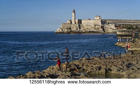 Stock Photograph - Fishing along the coast with Morro Castle in the distance; Havana, Cuba. Fotosearch
