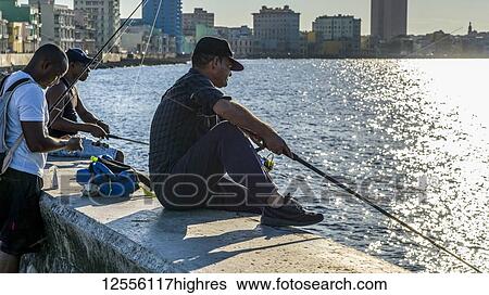 Stock Photograph - Fishing along the Malecon at dusk; Havana, Cuba. Fotosearch