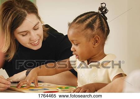 Stock Photography - Girl puts together a puzzle. Fotosearch