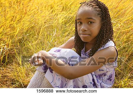 Girl sits in yellow field View Large Photo Image Stock Photo - Girl sits in yellow field. Fotosearch