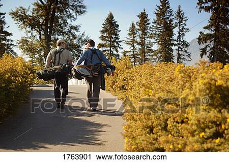 Golfers carry golf bags View Large Photo Image Stock Image - Golfers carry golf bags. Fotosearch