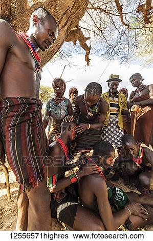 Stock Photograph - Hamer men getting their faces painted ahead of a bull jumping ceremony, which initiates a boy into manhood, in the village of Asile; Omo Valley, Ethiopia. Fotosearch