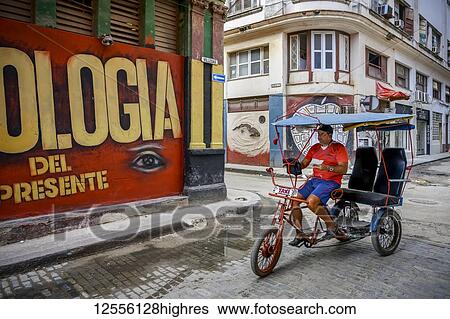 Stock Photograph - Man cycling on a pedicab on the streets of Havana; Havana, Cuba. Fotosearch