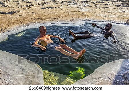 Stock Photograph - Men bathing in a pool of brine in the Salt flats of Lake Karum (Lake Assale), Danakil Depression; Afar Region, Ethiopia. Fotosearch