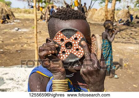 Mursi boy showing a lip plate in a village in Mago National Park; Omo Valley, Ethiopia View Large Photo Image Stock Photograph - Mursi boy showing a lip plate in a village in Mago National Park; Omo Valley, Ethiopia. Fotosearch