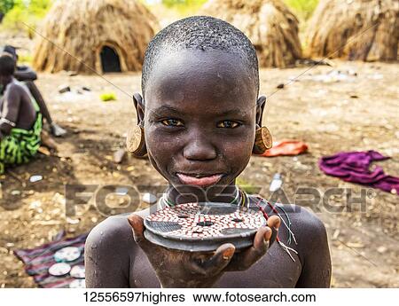 Mursi boy showing a lip plate in a village in Mago National Park; Omo Valley, Ethiopia View Large Photo Image Stock Photograph - Mursi boy showing a lip plate in a village in Mago National Park; Omo Valley, Ethiopia. Fotosearch