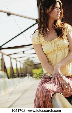 Stock Image - Sitting on a bridge rail. Fotosearch