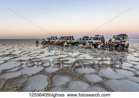 Stock Photograph - Tourists in front of four-wheel drive vehicle on the salt flats of Lake Karum (Lake Assale) at sunset, Danakil Depression; Afar Region, Ethiopia. Fotosearch