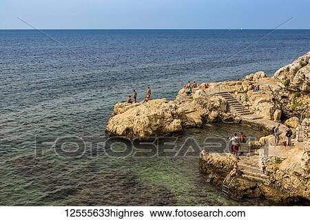 Tourists swimming and sunbathing along the coast of the Adriatic Sea; Rovinj, Croatia View Large Photo Image Stock Photograph - Tourists swimming and sunbathing along the coast of the Adriatic Sea; Rovinj, Croatia. Fotosearch