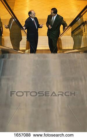 Two men have a discussion on an escalator View Large Photo Image Stock Photo - Two men have a discussion on an escalator. Fotosearch