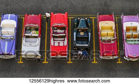 Stock Photograph - Vintage convertible cars parked in a row in a parking lot; Havana, Cuba. Fotosearch