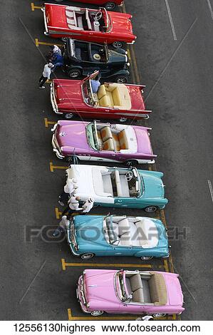 Stock Photograph - Vintage convertible cars parked in a row in a parking lot; Havana, Cuba. Fotosearch