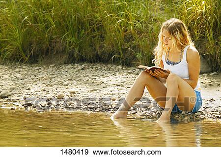 Stock Photo - Woman reading a book by the water. Fotosearch