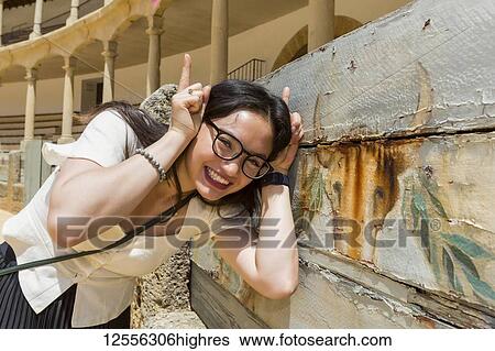 Stock Photograph - Young female tourist poses with bull image at bull fighting ring, Plaza de Toros de Ronda; Ronda, Malaga, Andalucia, Spain. Fotosearch