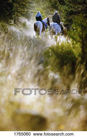 Stock Image - Two people on horseback. Fotosearch