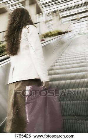 Stock Photography - Woman on an escalator. Fotosearch