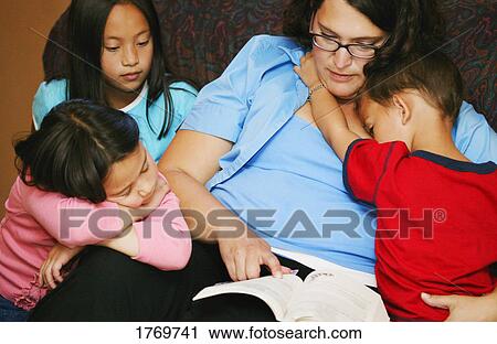 Stock Image - A mother reading to her children. Fotosearch