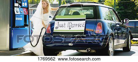 Stock Image - Bride fills car with gas. Fotosearch