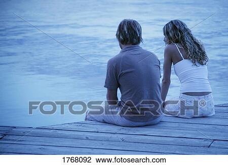 Couple sit on a dock View Large Photo Image Stock Image - Couple sit on a dock. Fotosearch
