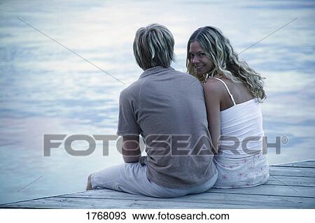 Couple sit on a dock together View Large Photo Image Stock Image - Couple sit on a dock together. Fotosearch