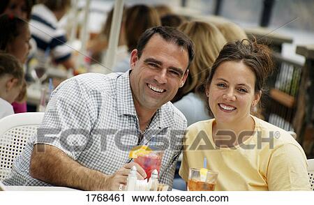 Stock Image - Couple sits outside with drinks. Fotosearch
