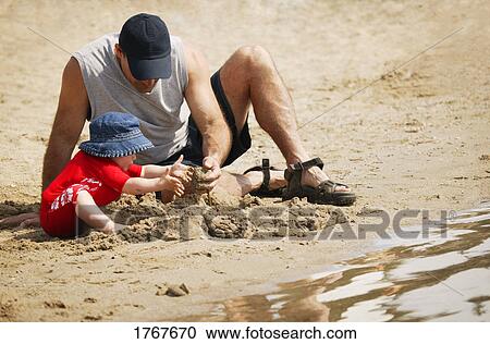 Father and child play in sand View Large Photo Image Stock Image - Father and child play in sand. Fotosearch